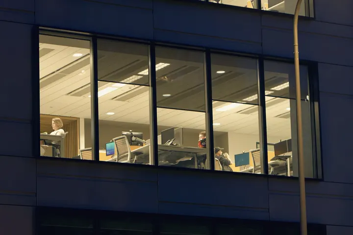 Office windows lit at night, a whole team still at work