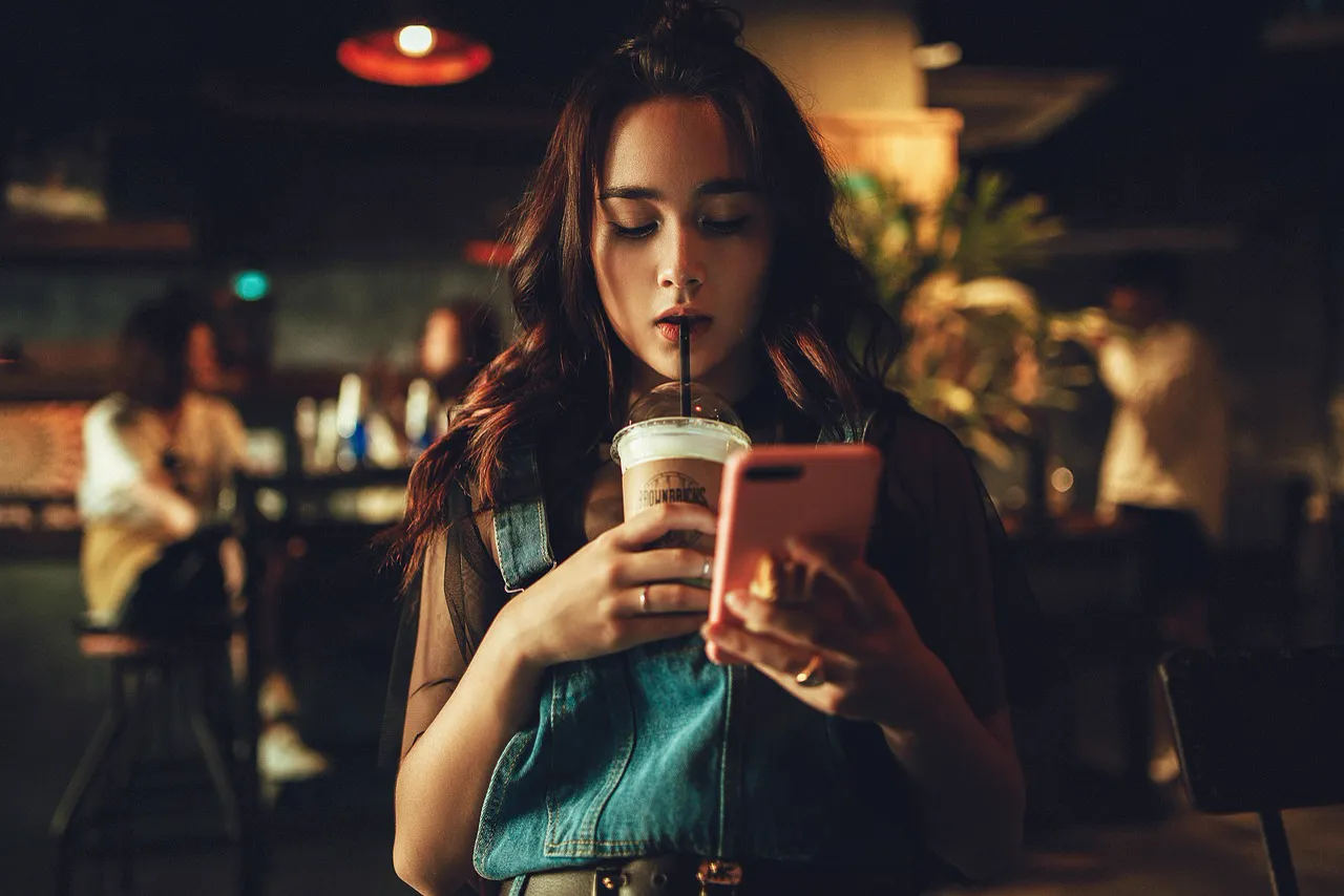 A woman in a café, smiling at her phone