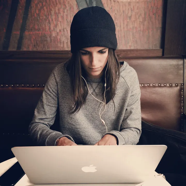 A woman in a hoodie working on her laptop, focused